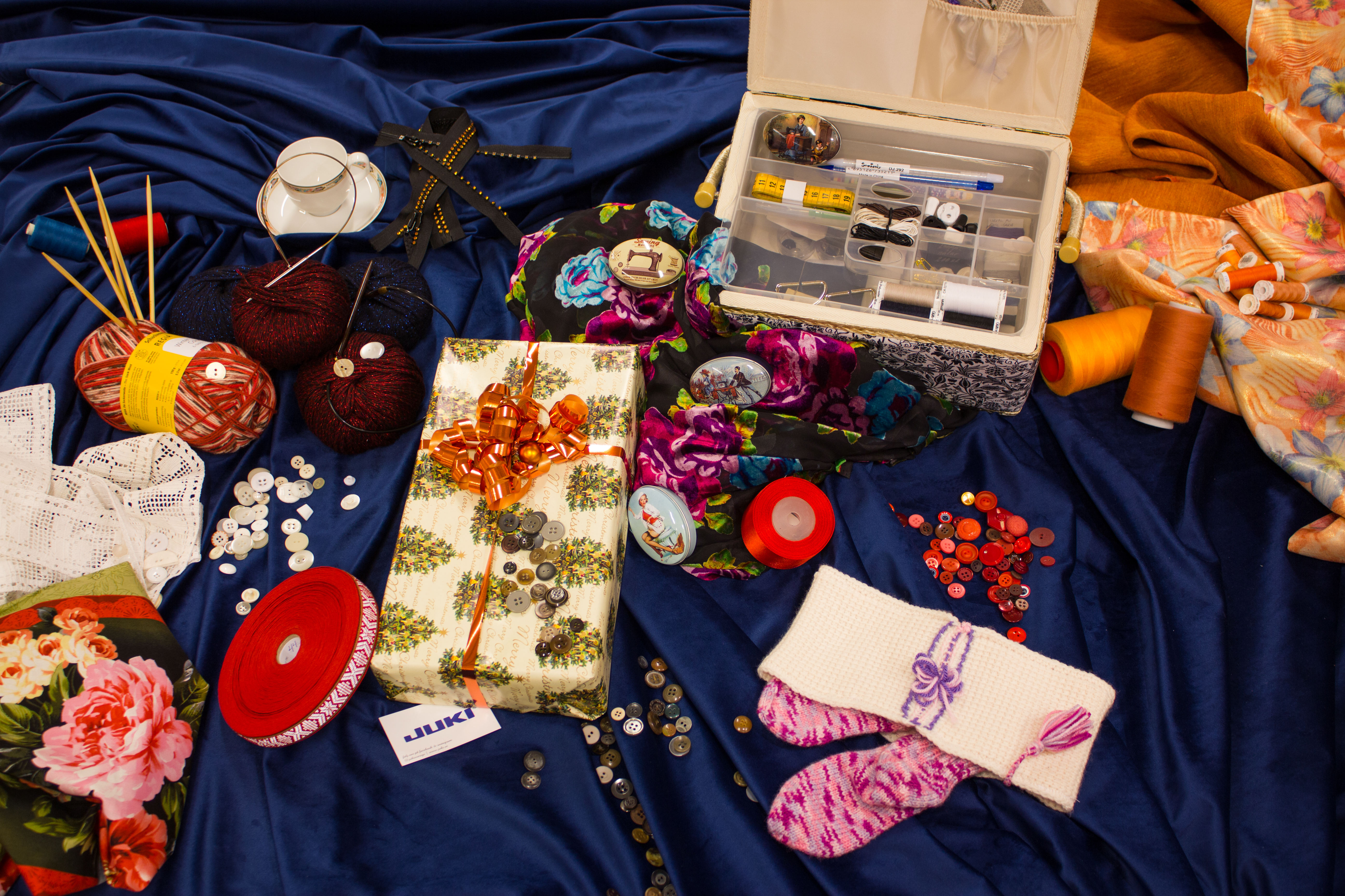 Dekorationsbild med sömnadstillbehör på en blå textilie. 